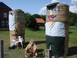 boerenkunst. op het paardenwagentje in het midden liggen klassieke korenschoven, het boerenduo links is van deze tijd